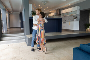 Naklejka premium Diverse couple hugging each other on stone floor near column by kitchen island at home