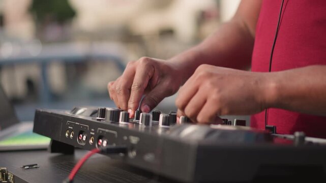 Disc jockey performing, Street performance with rhythmic mixing under warm afternoon sunlight, Disc jockey skillfully adjusting controls on portable mixer amidst energetic city environment