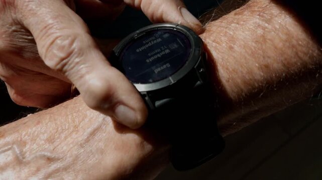 close-up of senior citizen hands using buttons on a technical watch to search for health information from exercise