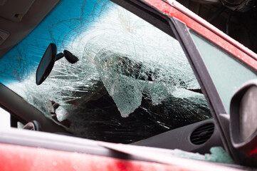 Damaged crashed vehicle after car accident collision, broken window, cars inside a towing trailer driving to a junkyard 