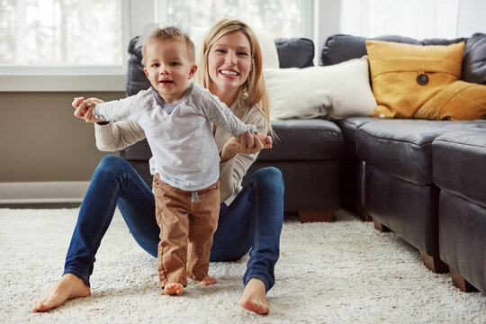 Mom, toddler and learning to walk holding hands in home for education or bonding in living room. Portrait, development and mother teaching kid or child for help, movement and support or first steps