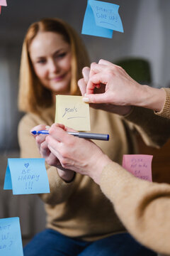 Woman writing positive affirmations on sticky notes in front of mirror