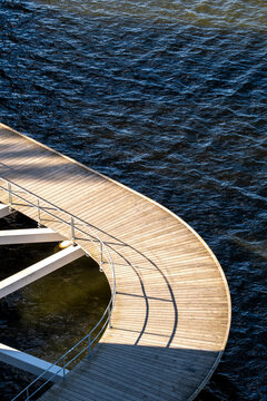 Minimal urban architecture boardwalk curve with railing beside water showing abstract design and rich texture in clean modern waterfront composition