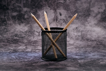 Natural wood pencils stand ready in a cylindrical black mesh cup, their pointed tips hinting at creativity