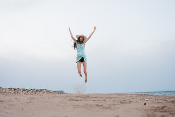 Obraz premium Young woman jumping with joy on summer beach