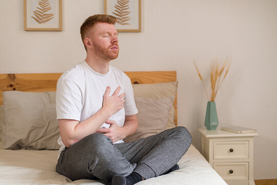 Man practicing mindful breathing and relaxation in a calm bedroom