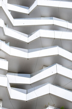 Modern architecture facade with white balconies and repeating pattern geometry lines across structure creating abstract residential background