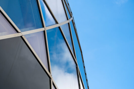 Minimal modern architecture facade at corner with glass reflecting blue sky showing geometry for abstract background with copy space