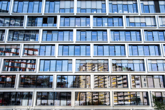 Modern office architecture facade with windows and glass grid pattern plus reflection creating abstract corporate background for branding