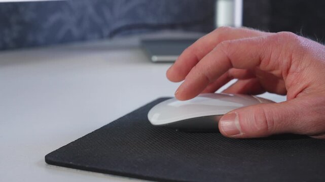 Hand moving computer mouse on desk at modern home office