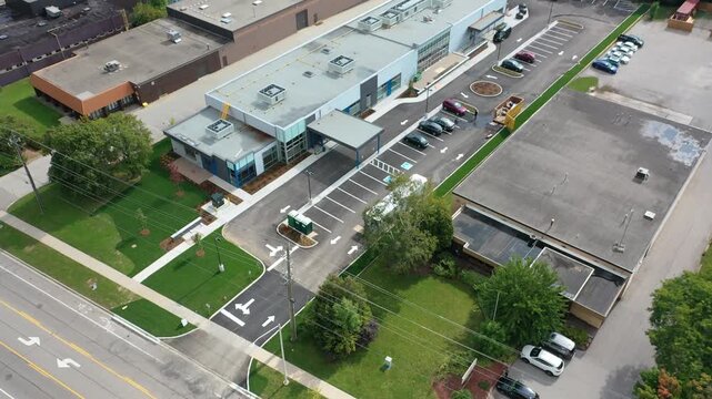 High angle aerial perspective flying over a modern commercial building and industrial park, showcasing warehouses, parking lots, and streets in a typical american suburban business district