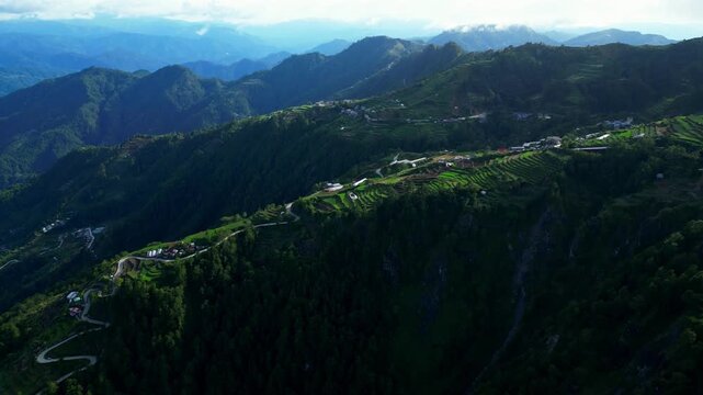 Forward slow moving aerial shot over Halsema Highway Atok Benguet Philippines leading toward expansive vegetable farms