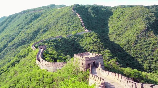 Scenic outdoor view of the Great Wall of China winding through mountains, ancient stone architecture surrounded by natural landscape, peaceful atmosphere, cultural heritage scenery, clear daylight