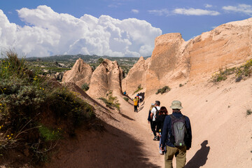 Tourists walking on a trail between massive rock formations in the unique valleys of Goreme, Turkey