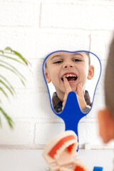 Little boy looking in the mirror at his loose primary tooth.