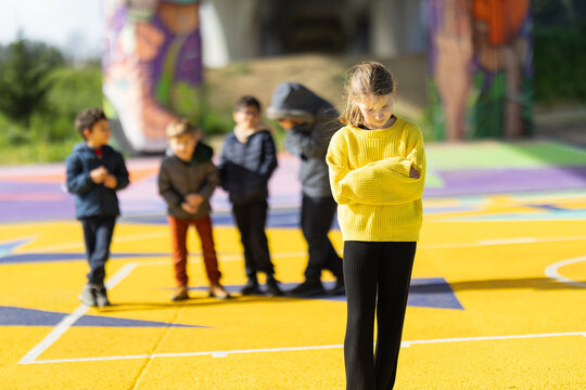 Girl feeling excluded by peer group on colorful playground