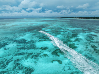 Aerial view of jet skis over shallow turquoise sea with reef in Zanzibar. Clear tropical water,...