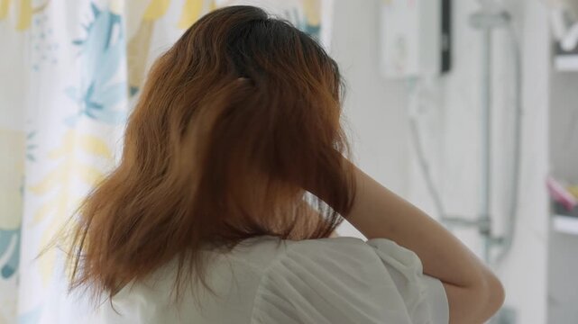 Rear view of a woman scratching her scalp intensely, indicating an itchy scalp, concept of stress-related hair loss