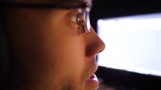 Male gamer playing in first person shooter on computer at home. Young man in headphones spending time at online video game on pc at night. Concept of cyberspace, competition and tournament. Slow mo