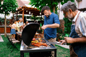 Fototapeta premium Father Reacting to Heat While Grilling Food at Outdoor Family Barbecue