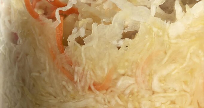 Glass jar with fermented cabbage and carrot, sauerkraut, sauer kraut, healthy vegan crunchy probiotic. Close-up footage on the rotating table.
