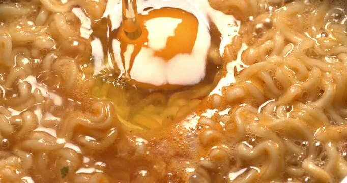 Egg is added to boiling water with instant noodles. The process of making Korean spicy  ramyong soup.