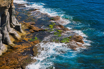 Shoreline and turquoise sea at Badouzi Coastal Park, beautiful natural area in Keelung, Taiwan. Scenic location with unique rock formations and green algae, creating striking contrast with blue water © Leilani