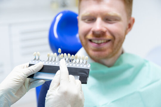 Dentist choosing veneers shade for smiling patient