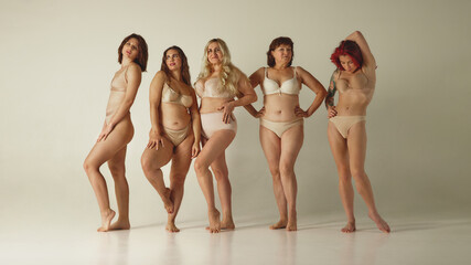 Group of diverse women posing confidently in lingerie on neutral studio background. Concept of body positivity, age diversity, inclusive fashion campaigns, lingerie marketing, editorial and ads use.