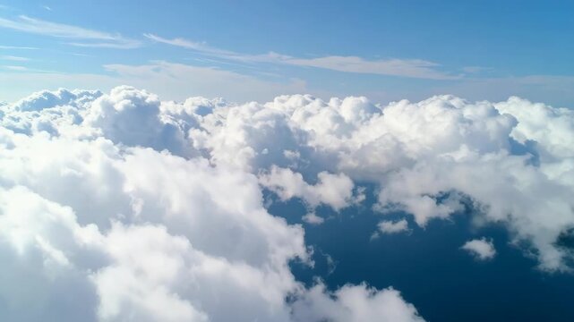 Fluffy white clouds drift over deep blue ocean water from an aerial view.