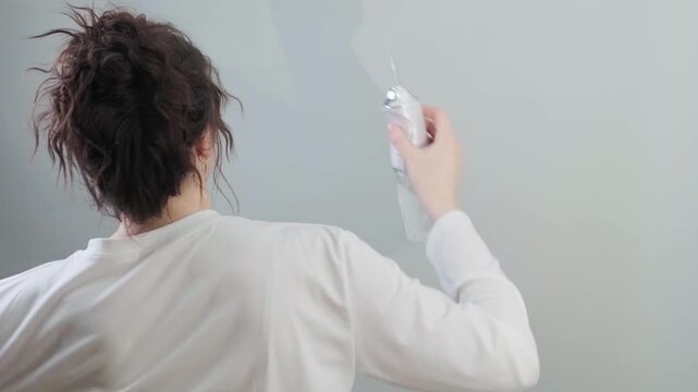 Morning routine with good vibes. Woman with a bun uses a water flosser while dancing and singing starting the day with positivity.