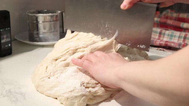Hands prepare ciabatta bread by shaping the dough. The dough shows clear signs of fermentation as it is worked. Observe the texture develop with each step in the process.
