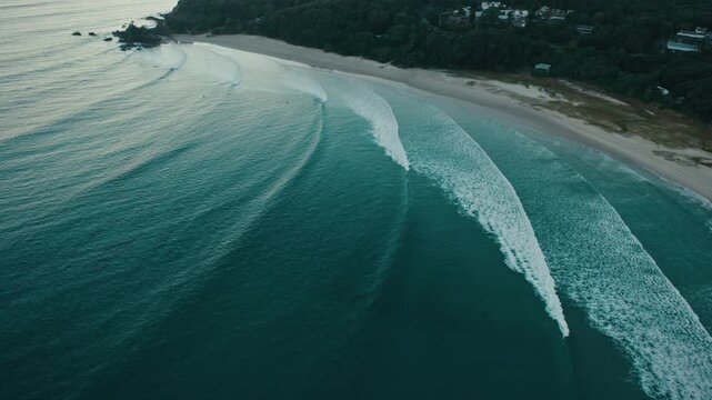 Top down drone angle establishing parallel wave lines peeling toward Byron Bay beach
