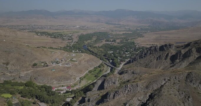 Aerial view of the stunning mountain terrain, intertwined with a flowing river and lush green trees in the valley, Samtskhe-Javakheti, Georgia.