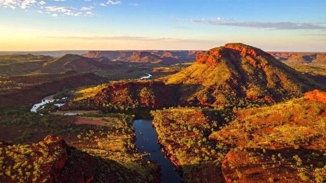 Aerial view of a rugged, red landscape with a winding river at sunset.