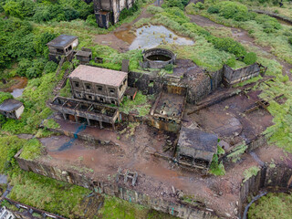 High angle aerial view of the abandoned 13 Levels mining site near Jiufen, Taiwan, revealing layered industrial ruins, concrete structures, and geometric patterns embedded in a rugged coastal landscap