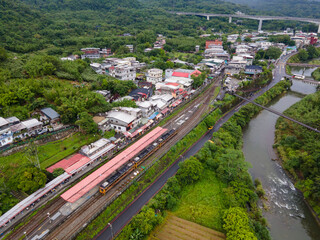 Aerial view of Shifen Train Station in Taiwan with a train on the tracks, people gathered along the railway, and colorful sky lanterns floating above, capturing a lively cultural scene.

