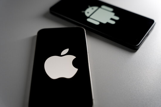 Smartphones displaying Apple and Android logos on black screens with focused view on Apple operation system
