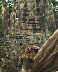 Fototapeta premium Male Traveler At Bayon Face Tower In Ancient Angkor Jungle Temple