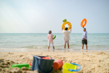 Obraz premium In holiday, Family members jumping and throwing inflatable rings into the air