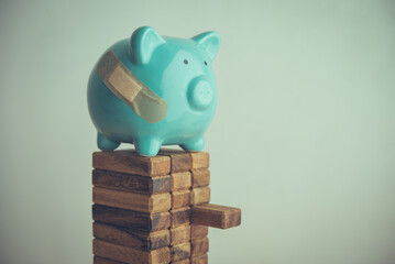 Injured piggy bank on risk tall stack woods. Personal financial problem from high interest rate loan, loss investment, high expense, economy crisis effect to savings, financial risk management concept