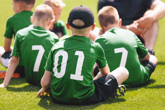 Youth Soccer Team Sitting on Grass. Kids Wearing Green Football Jerseys During Training or Match Break