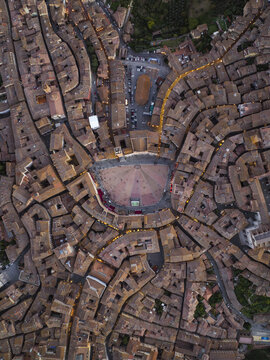 Aerial view of Siena, Tuscany, Italy. Piazza del Campo's unique shell shape encircled by the medieval architecture of the terracotta-toned buildings in the golden light.