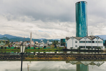 Obraz premium Tranquil city reflections cape with mountains. Peaceful waters mirror modern buildings and nature. Calm water perfectly reflects skyline with scenic mountain background