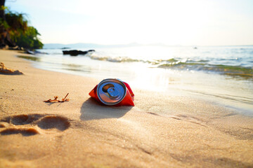 Obraz premium Crumpled soda can on sand beach at sea. Discarded broken soda can at seashore. Environmental pollution, sea water pollution. Rubbish on beach. Clean beach from trash. Empty crumpled can from drink.