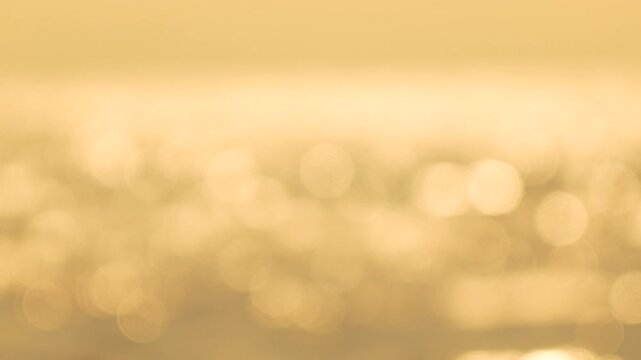 Sunlight water bokeh, shimmering golden light reflecting on calm ocean waves, serene peaceful abstract background