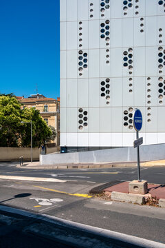 Empty urban street intersection under open sky with modern white facade pattern and holes creating a clean architectural scene with copy space