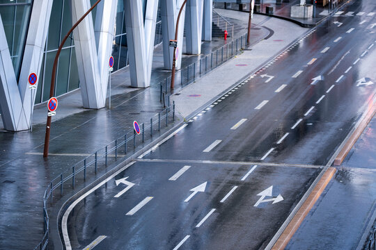 Empty urban roadway in perspective with wet asphalt lanes traffic arrows and infrastructure markings creating a clean modern transport background copy space