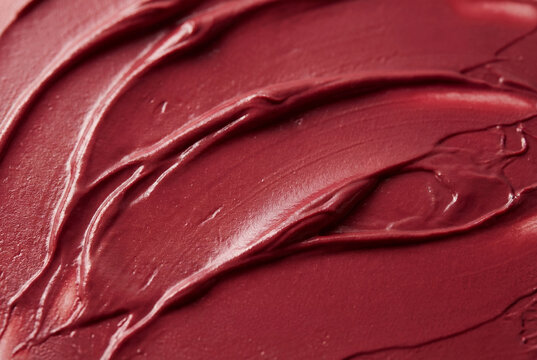 Deep berry red cosmetic cream texture smeared on surface with smooth velvety artistic strokes