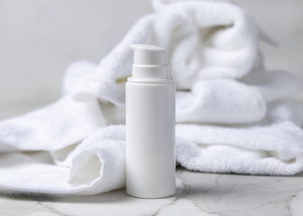 Mockup of white blank pump cosmetic bottle near white bath terry towel in hotel bathroom